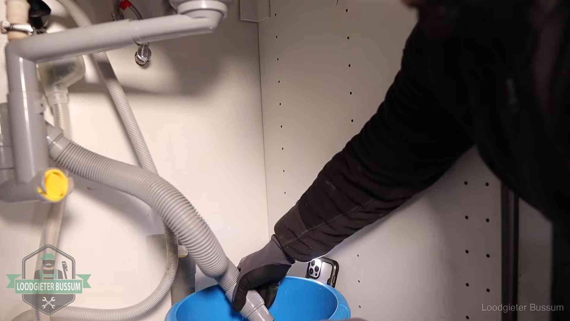 Afvoerslang loopt leeg in een emmer onder de gootsteen in Bussum, een klus die je zelf kunt doen