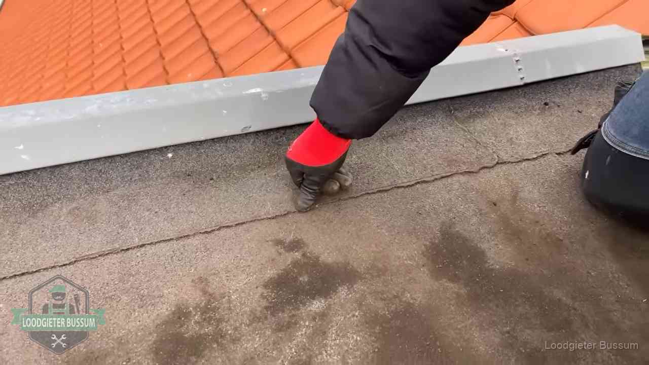 Lekkage bij de naad van een plat dak in Bussum Vakman wijst een naad met vochtplekken aan op een bitumen plat dak in Bussum