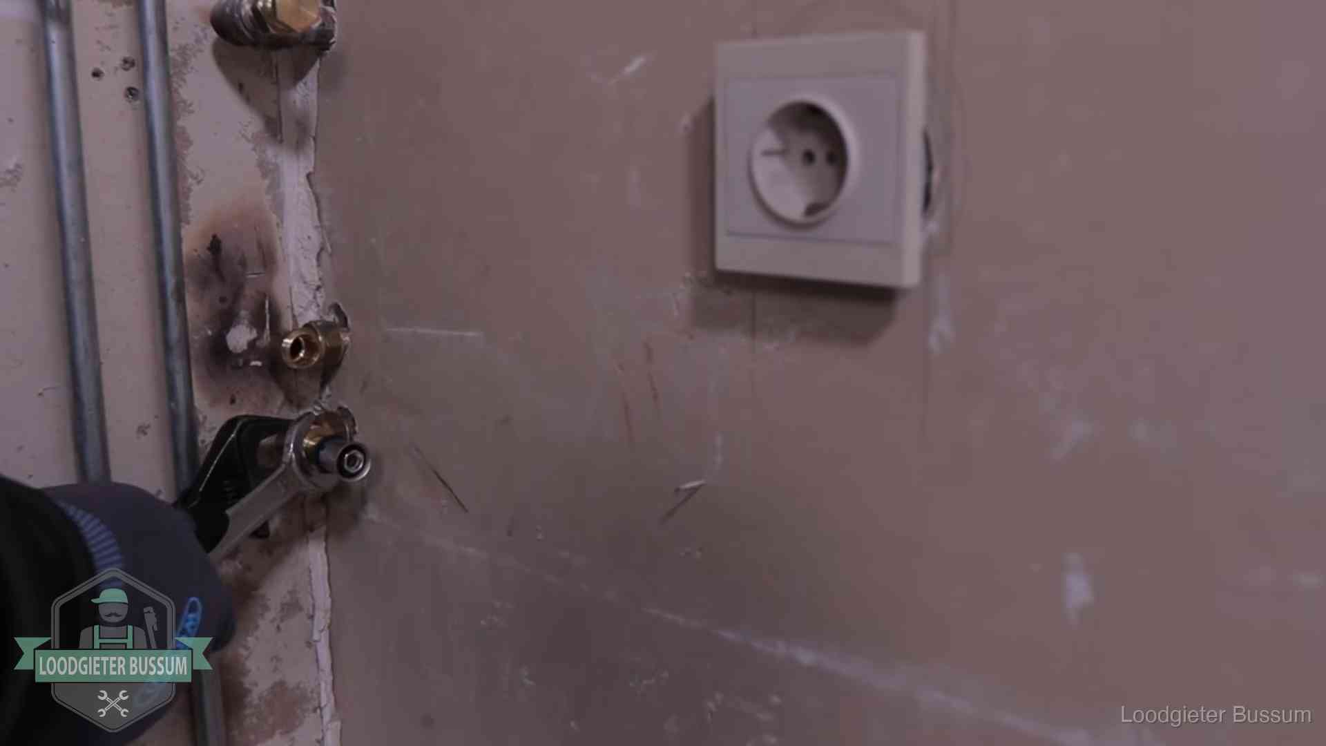 Monteur draait een perskoppeling vast op een leidingaansluiting in Bussum