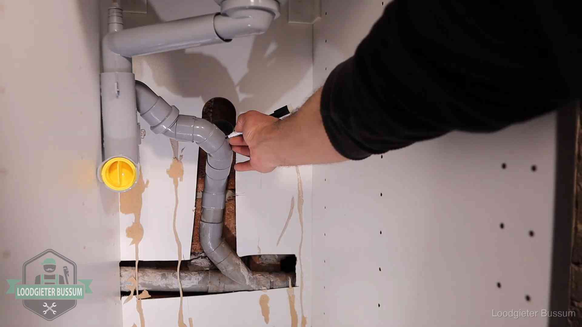 Loodgieter markeert een pvc-afvoerbuis onder een gootsteen in Bussum