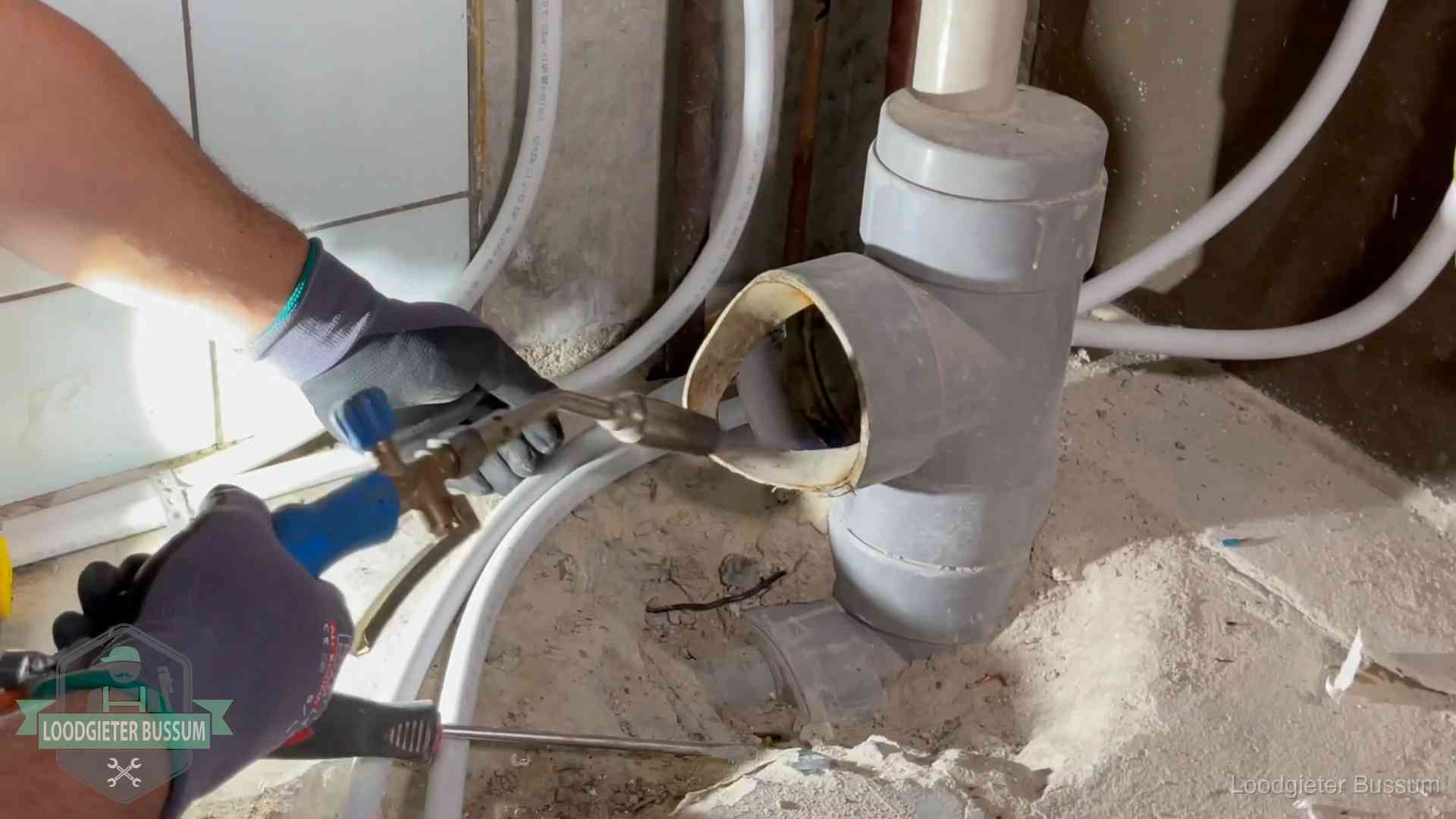 Loodgieter werkt met brander en messing kraanwerk aan leidingen in Bussum