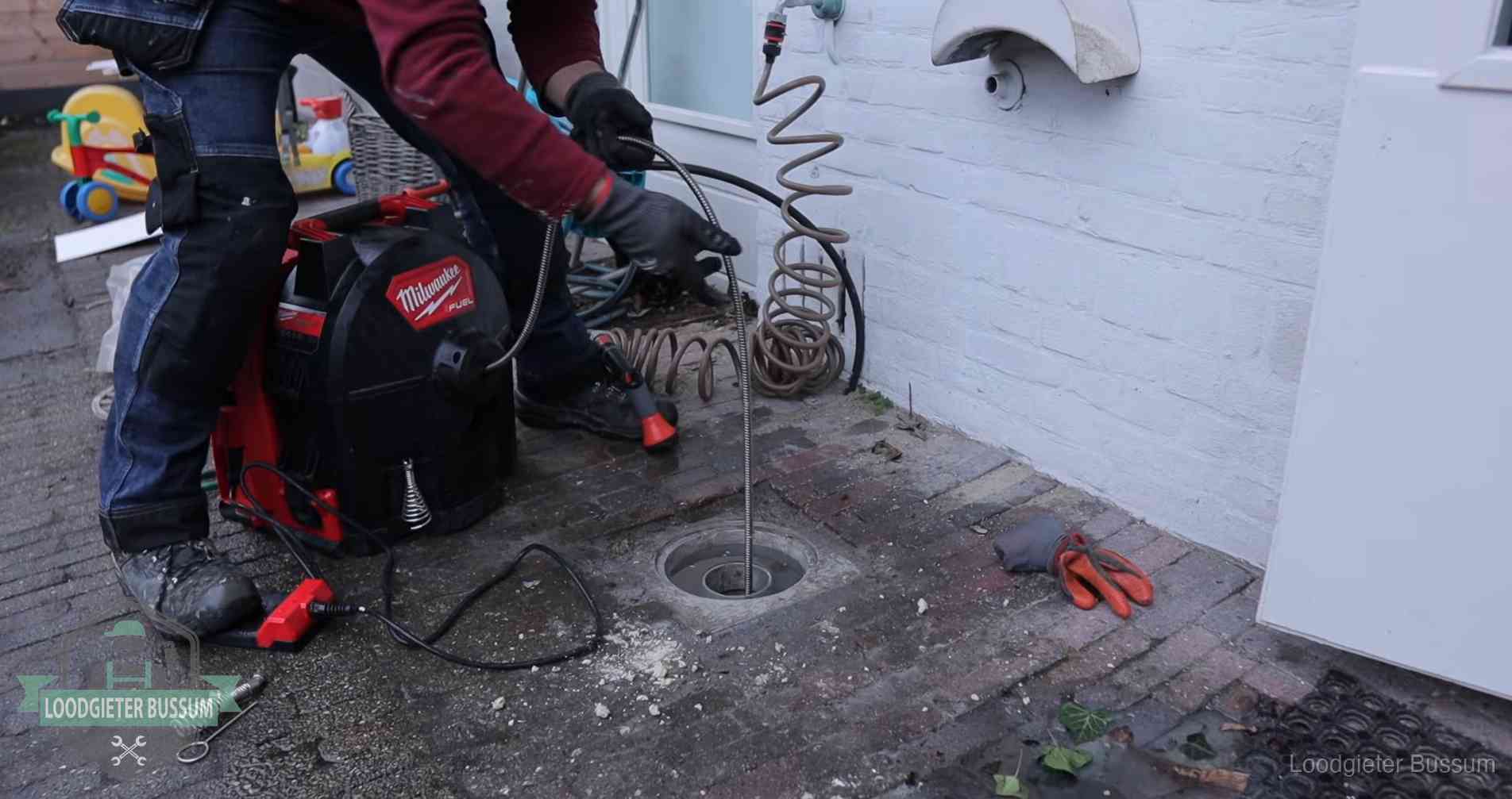Ontstoppingsputje in de bestrating naast de gevel van een woning in Bussum