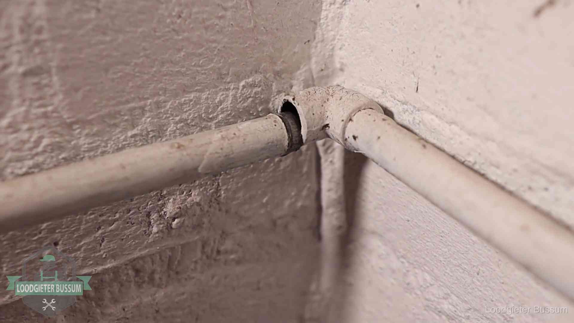 Oude geverfde waterleiding met een losliggende fitting in een woning in Bussum