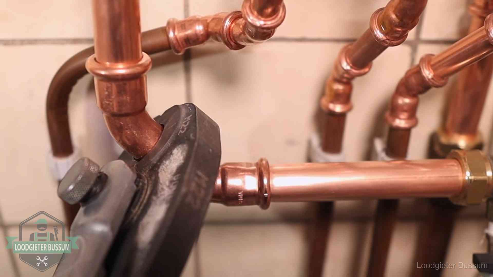 Persmachine perst een koperen fitting op nieuw leidingwerk in Bussum