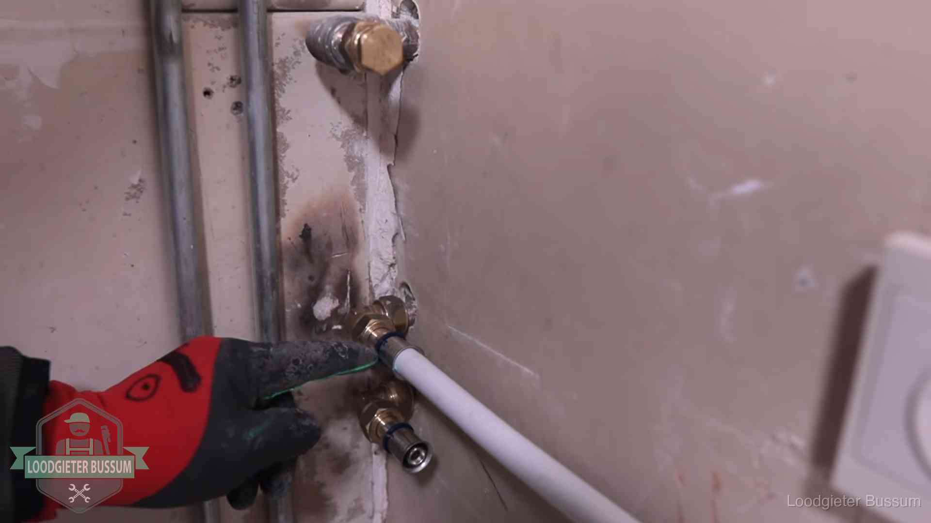Loodgieter wijst de persfitting op nieuwe muuraansluitingen aan in een woning in Bussum