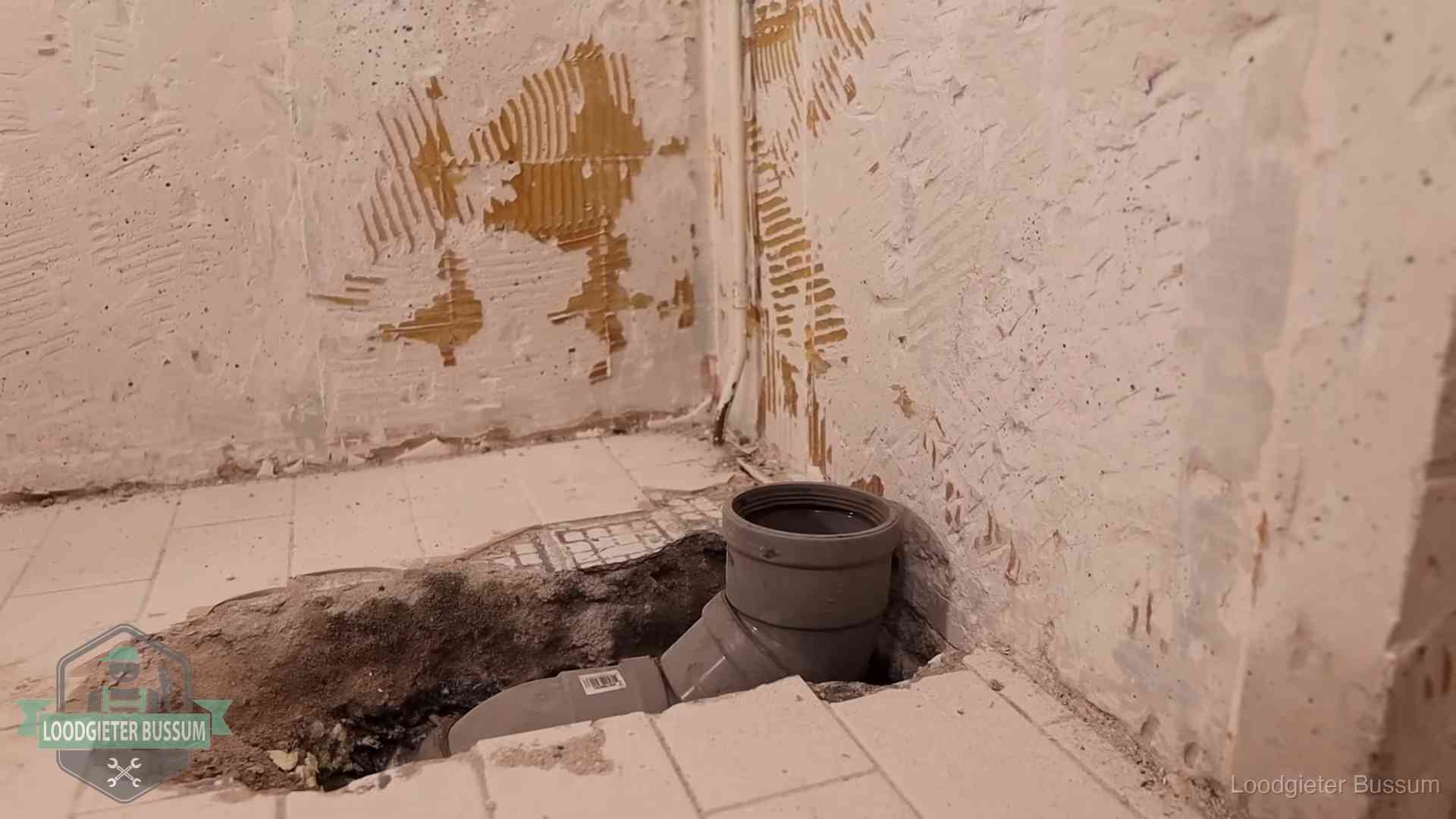 Opengebroken vloer met een nieuwe pvc-rioolbocht in een gegraven sleuf in Bussum