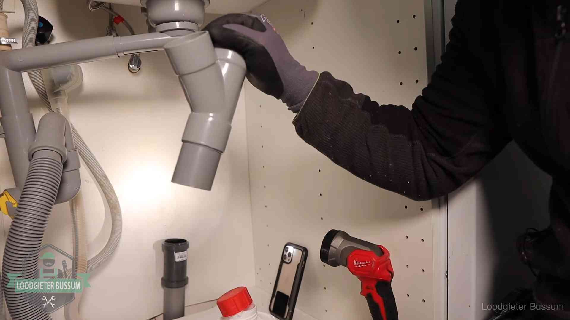 Loodgieter demonteert het sifon- en afvoerwerk onder een gootsteen in Bussum bij stankklachten