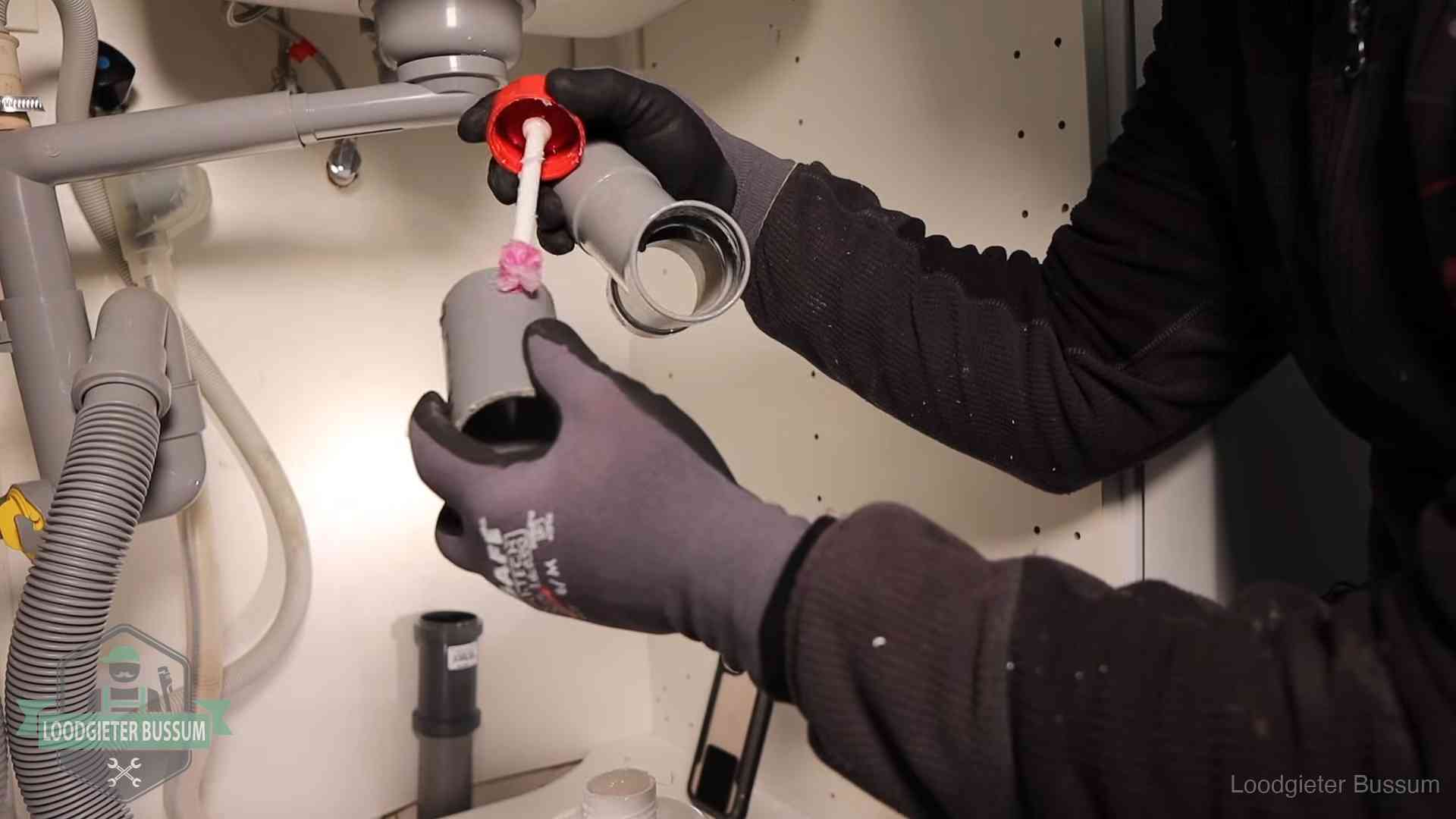Loodgieter demonteert en reinigt de sifon onder een keukenkast in Bussum