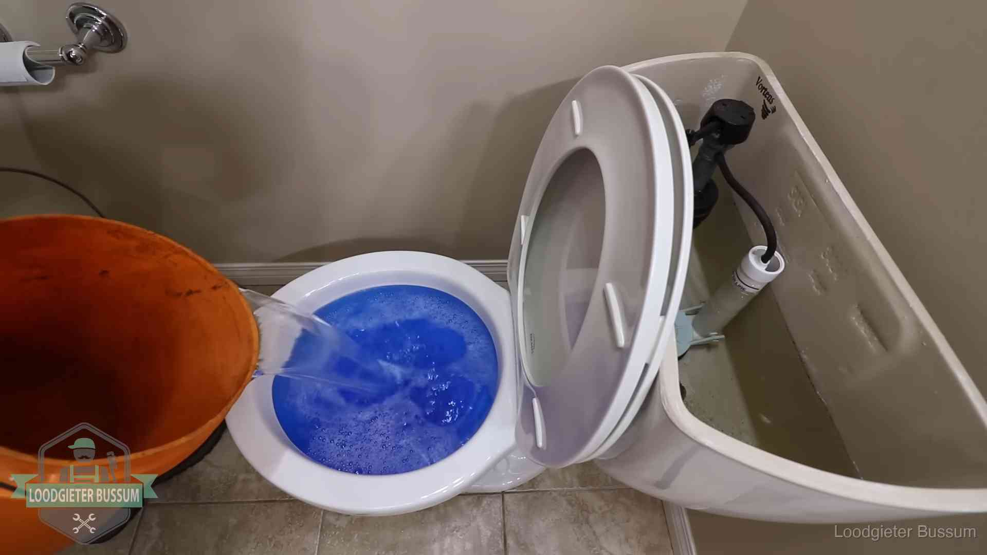 Water bij de wc-pot wordt met een emmer weggewerkt om schade te beperken in Bussum